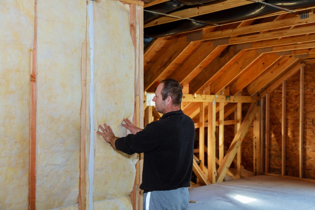 Worker thermally insulating a house